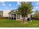 Back exterior showcasing a screened porch, brick patio, and lush greenery, offering a serene outdoor living space at 6119 Castlecove Rd, Charlotte, NC 28278