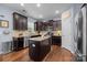 Modern kitchen with dark wood cabinets, granite countertops, and stainless steel appliances at 6119 Castlecove Rd, Charlotte, NC 28278