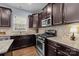 Well-lit kitchen showcasing granite countertops, dark cabinets, and stainless steel appliances, perfect for the modern home at 6119 Castlecove Rd, Charlotte, NC 28278