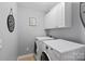 Efficient laundry room with front-loading machines and built-in storage cabinets for organization at 6309 Crosshall Pl, Waxhaw, NC 28173