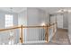 Upstairs hallway with carpet, wood railing, and bright lighting at 6309 Crosshall Pl, Waxhaw, NC 28173