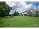 Expansive backyard with lush lawn, play set, covered patio, and mature trees at 6309 Crosshall Pl, Waxhaw, NC 28173