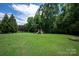 Large grassy backyard showcasing mature trees and a playset for outdoor fun at 6309 Crosshall Pl, Waxhaw, NC 28173