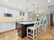 Contemporary kitchen island with marble countertop and seating, with hardwood floors and modern lighting at 6647 Gaywind Dr, Charlotte, NC 28226