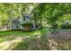 View of the house's light blue siding and well-maintained lawn with mature trees, creating a serene and private outdoor space at 7226 Reedy Creek Rd, Charlotte, NC 28215