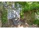 A storage shed with double doors and a ramp surrounded by a garden, nestled amongst surrounding trees in the backyard at 7226 Reedy Creek Rd, Charlotte, NC 28215