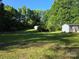 Lush backyard with sheds surrounded by mature trees and manicured green grass at 850 Meadowbend Dr, York, SC 29745
