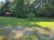 Expansive front yard features lush green grass, mature trees, and a charming wooden storage shed at 850 Meadowbend Dr, York, SC 29745