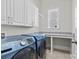 Well-lit laundry room featuring a front load washer/dryer set, folding table, and storage cabinets at 9750 Briarwick Ln, Charlotte, NC 28277