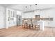 Open concept kitchen offers white cabinets, stainless steel refrigerator, island with seating, and hardwood floors at 104 Arbor Dr, Waxhaw, NC 28173