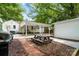 Charming backyard featuring a covered patio, wooden picnic table, and brick walkway surrounded by lush greenery at 108 Greenwood Ave, Belmont, NC 28012