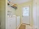 Bright laundry room with white appliances, a storage shelf, and access to the outdoors at 11718 Battery Pl, Charlotte, NC 28273