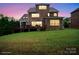 Backyard view of a multi-story brick home featuring an expansive lawn and wooden deck at dusk at 13102 Indigo Run Ct, Charlotte, NC 28278