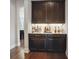 Stylish bar area with dark wood cabinets, granite countertops, and a variety of liquor bottles on display at 13102 Indigo Run Ct, Charlotte, NC 28278