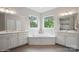Bright bathroom with dual vanities, a soaking tub, and large windows offering wooded views at 13102 Indigo Run Ct, Charlotte, NC 28278