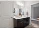 Bright bathroom featuring double sinks, a large mirror, dark wood cabinets, and a doorway leading to another room at 13102 Indigo Run Ct, Charlotte, NC 28278