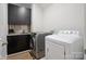 Modern laundry room with sleek black cabinets, a stainless steel sink, and a front-load washer and dryer at 13102 Indigo Run Ct, Charlotte, NC 28278