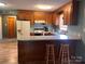 Eat-in kitchen features wood cabinets, white appliances, a breakfast bar, and a tiled floor at 1351 Hardin Rd, Dallas, NC 28034