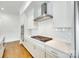 Gourmet kitchen with gas cooktop, stainless vent hood, white cabinets and countertops, and hardwood floors at 13702 Tranquil Day Dr, Matthews, NC 28105