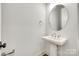 Comfortable powder room features a pedestal sink, oval mirror, and modern fixtures set against a soothing light grey at 13702 Tranquil Day Dr, Matthews, NC 28105