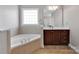 Cozy bathroom features a soaking tub with tile surround and vanity with dark wood cabinets at 15430 Waterfront Dr, Huntersville, NC 28078