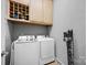 Well-organized laundry room with white front load machines, storage cabinet, and gray walls at 15430 Waterfront Dr, Huntersville, NC 28078