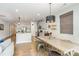 Open-concept dining area with a rustic table, modern lighting fixture, and adjacent kitchen at 1813 Shelbourne Way, Fort Mill, SC 29707