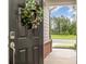 View of the front door with decorative wreath, digital lock, and a peek at lush greenery nearby at 1813 Shelbourne Way, Fort Mill, SC 29707