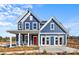 Charming two-story blue home with white trim, a red front door, and well-manicured landscaping at 2004 Waxhaw Crossing Dr, Waxhaw, NC 28173