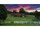 Scenic backyard view of the property featuring lush green lawns, a white fence, and a colorful sunset at 2448 Moss Farm Rd, Hickory, NC 28602