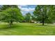 Spacious front yard with mature trees framing a charming brick home, creating a serene and inviting atmosphere at 2448 Moss Farm Rd, Hickory, NC 28602