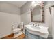 Charming half-bath features a pedestal sink with a floral-framed mirror and wainscoting at 2702 Oxborough Dr, Matthews, NC 28105