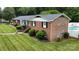 An aerial view of the brick home, showing the expansive yard, pool, and manicured landscaping at 2968 Grace St, Claremont, NC 28610