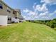 A well-maintained backyard, featuring a grassy lawn that slopes down to a tree line with a partial view of a neighboring home at 3306 Yarmouth Ln, Gastonia, NC 28056