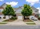 Front exterior featuring townhomes with brick and siding, well-maintained landscaping, and attached garages at 3306 Yarmouth Ln, Gastonia, NC 28056