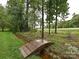 Backyard with a small wooden bridge over a stream, enhancing the natural beauty of the property at 3409 Valdosta Ct, Monroe, NC 28110