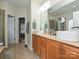 This bathroom features double sinks with a large mirror, wood cabinets, and tile flooring at 3409 Valdosta Ct, Monroe, NC 28110
