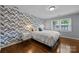 Stylish bedroom showcasing accent wall, hardwood floors, window, nightstand, and comfortable queen bed at 4106 Castlewood Rd, Charlotte, NC 28209