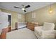 Cozy Bedroom showcasing crib, changing table on dresser, comfortable chair, and overhead ceiling fan at 4106 Castlewood Rd, Charlotte, NC 28209