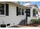 Close up shot of a charming white brick home entrance featuring a modern black door and stairs at 4106 Castlewood Rd, Charlotte, NC 28209