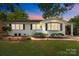 Charming single-story home featuring a white brick facade, manicured landscaping, and a covered carport at 4106 Castlewood Rd, Charlotte, NC 28209
