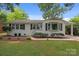 Charming single-story home featuring a white brick facade, manicured landscaping, and a covered carport at 4106 Castlewood Rd, Charlotte, NC 28209