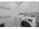 Functional laundry room equipped with washer, dryer, storage cabinets, and hanging racks at 4106 Castlewood Rd, Charlotte, NC 28209