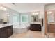 Bright bathroom featuring dual vanities, soaking tub, glass enclosed shower, and neutral tile at 5812 Dinsmore Ln, Belmont, NC 28012