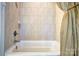 Clean white bathtub with a shower head surrounded by light beige tiles and a shower curtain at 5826 Natoma Rd, Lake Wylie, SC 29710