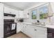 Bright kitchen features white cabinets, black appliances, and laminate flooring at 875 Marys Grove Rd, Cherryville, NC 28021