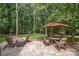 Backyard patio area with outdoor seating and a shade umbrella surrounded by mature trees at 104 Golden Bell Ct, Mooresville, NC 28117