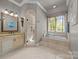 Bright bathroom with a bathtub, tiled shower, and vanity with sink and ornate mirror at 104 Golden Bell Ct, Mooresville, NC 28117