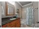 Bathroom featuring a vanity with dark granite countertop, a framed mirror, and tiled shower with glass door at 104 Golden Bell Ct, Mooresville, NC 28117