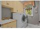 Well-lit laundry room with a front-load washer and dryer, sink, and cabinets at 104 Golden Bell Ct, Mooresville, NC 28117